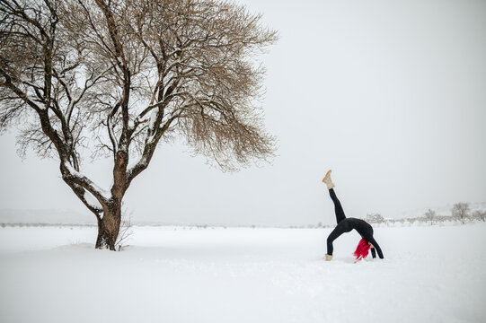 Woman doing yoga in One Legged Wheel pose in winter