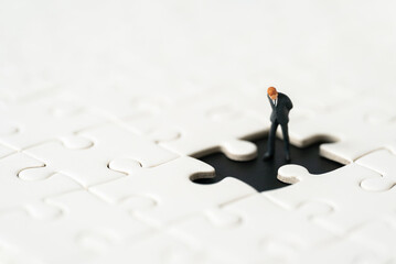 Miniature people Group Business man mini figures standing thinking on Jigsaw Puzzle white background copy space using as thinking business plan and how to solve problem Strategy Planning concepts