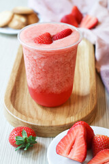 A glass of fresh cold iced blended organic strawberries juice on a wooden plate with its fruit, a healthy balance drink and for diet concept 
