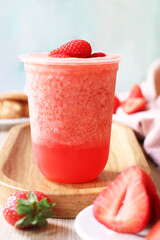 A glass of blended with iced of organic natural strawberries juice on a wooden plate with its fruit, a healthy balance drink and for diet concept
