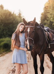 Portrait of young girl standing next to a horse looking at camera smiling.