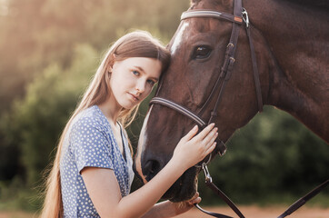 Obraz premium A young beautiful girl hugs a brown horse in the summer in nature in the summer