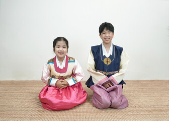 한복을 입고 웃으며 멍석 위에 앉아있는 아이들 Smiling children wearing Hanbok...