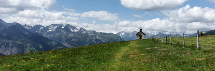 Obraz premium Panoramic view of the mountains. Small chapel on the mountain with a view of the Grossglockner in Austria