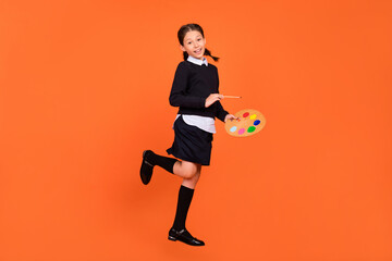 Full length body size view of pretty cheerful preteen girl drawing copy space isolated over bright orange color background