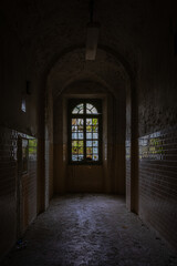 A corridor, with a mosaic window, inside an abandoned asylum
