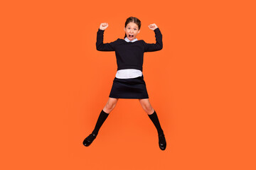Fototapeta na wymiar Full length photo of young girl happy positive smile celebrate victory success fists hands jump isolated over orange color background