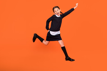 Full size photo of cheerful happy little girl jump up amazed shocked school isolated on orange...