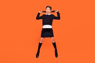 Fototapeta na wymiar Full body photo of young small girl jump up wear uniform funky face mood stick-out tongue isolated on orange color background