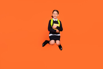 Fototapeta na wymiar Full body photo of brunette small amazed shocked girl jump up hold hug book isolated on orange color background