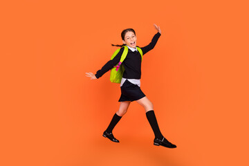 Fototapeta na wymiar Full length body size view of nice pretty funky cheerful schoolgirl jumping walking isolated over bright orange color background