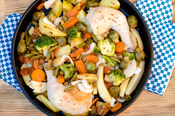 Baked vegetables with chicken leg on a baking sheet