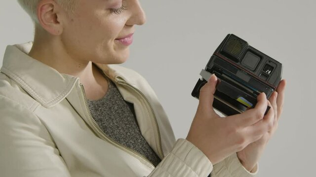 Side view of a female photographer loads instant film camera