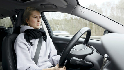 Young woman with natural look driving a passenger car on a German highway. The young woman shows various emotional reactions to the traffic event.