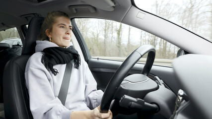 Young woman with natural look driving a passenger car on a German highway. The young woman shows various emotional reactions to the traffic event.