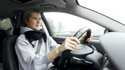 Young woman with natural look driving a passenger car on a German highway. The young woman shows various emotional reactions to the traffic event.