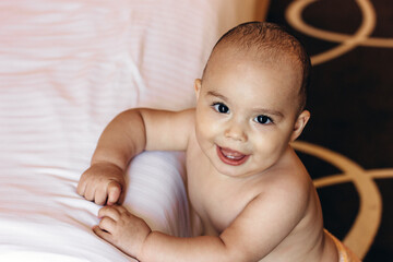 Sweet baby boy near bed in hotel room. Family vacation with children