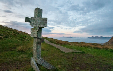 Old wooden sign with a wood trail on Norwegian mountain in sunset with copy space 