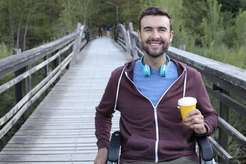 Young handsome man on a wheelchair drinking coffee to go