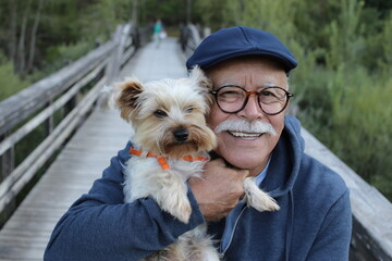 Ethnic senior man with small dog in the park