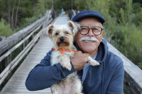Ethnic senior man with small dog in the park