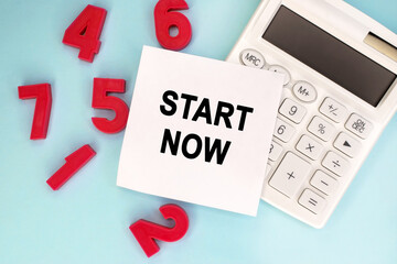 Start now is written on a piece of paper that lies on a white calculator near the red numbers....