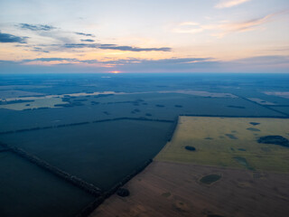 Drone photo of fields of rye, wheat in the countryside with setting sun in the background. Calm evening in the agricultural fields