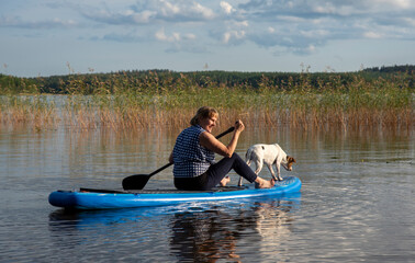 Fototapeta na wymiar Woman on paddle board with dog