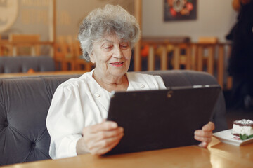 Elegant old woman sitting in a cafe and using a laptop