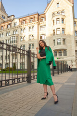 Stylish fashionable girl wearing trendy green costume posing at city street