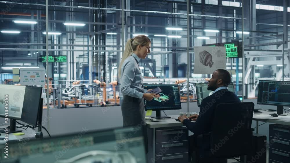 Fototapete Car Factory Office: Female Supervisor Talks with Male Automotive Engineer, Using Computer to Design Advanced 3D Models for High-Tech Engines. Automated Robot Arm Assembly Line Manufacturing Vehicles