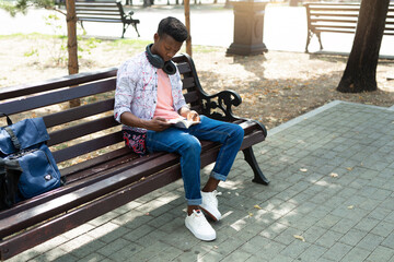 young african man reading a book in the park 