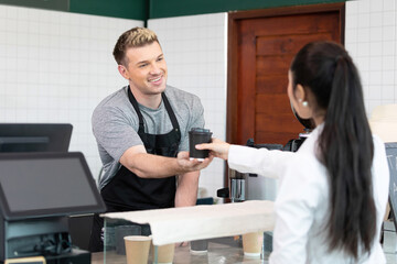 male barista giving a cup of coffee to customer in cafe or coffee shop