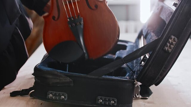 Young woman musician putting the violin in the case
