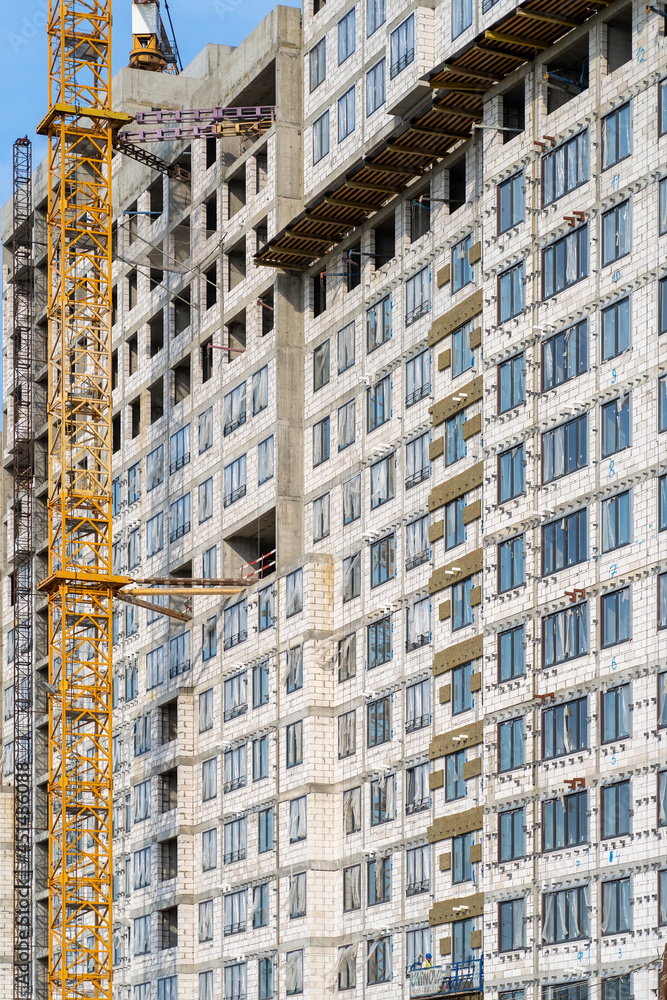 Poster view of frame part of metallic crane machinery attachment at windows of new residential building con