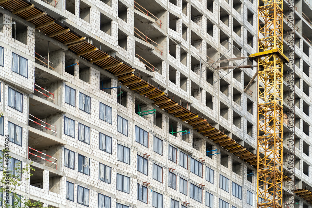 Poster view of frame part of metallic crane machinery attachment at windows of new residential building con