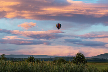 Hot air balloon over field at sunrise with amazing cloudscape sky