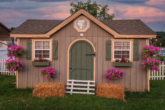 Beautifully decorated she shed with shutters and hanging flowers at sunset