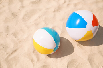 Bright beach balls on sand outdoors, above view