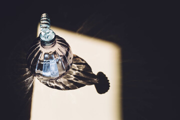 Crystal decanter on a beige background with shadows.