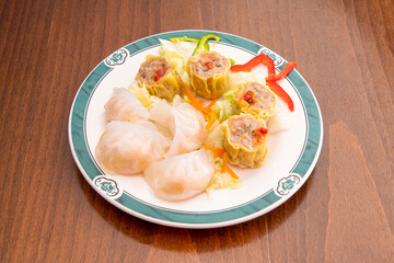 Assorted stuffed chinese dim sum dish with prawns, pork and vegetables on wooden table
