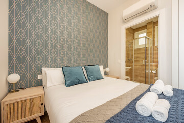 Bedroom with king size bed, adjacent shower room and over-the-door air conditioner in beautifully decorated vacation rental apartment