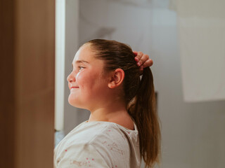 preteen girl combing her hair in front of the mirror