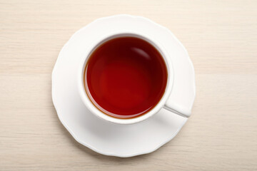 Freshly brewed rooibos tea in ceramic cup on wooden table, top view