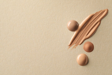 Samples of liquid skin foundations on beige background, top view. Space for text