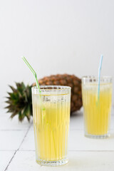 Delicious sweet refreshing pineapple juice with ice in glasses with a straw