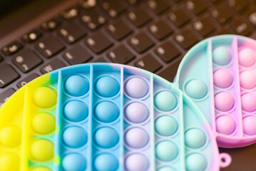 Multicolored antistress silicone Pop it.Toy on a keyboard laptop.Businessman or freelancer relaxes. closeup.relax popit