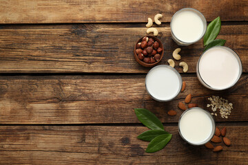 Fototapeta na wymiar Different vegan milks and ingredients on wooden table, flat lay. Space for text