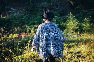 Girl with Poncho and Black Hat walking in the Woods