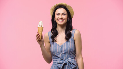 Smiling woman in sun hat holding delicious ice cream isolated on pink.